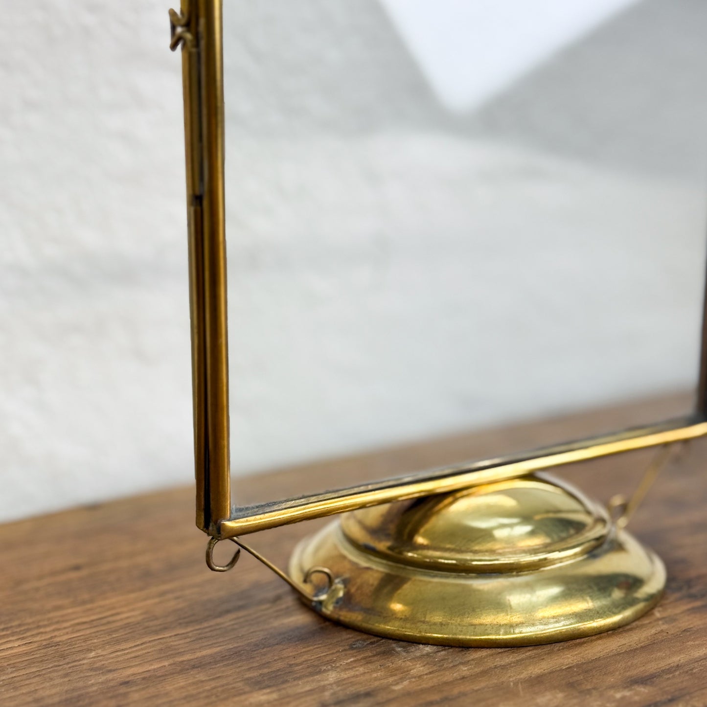 Brass-framed mirror on a wooden surface with a white background