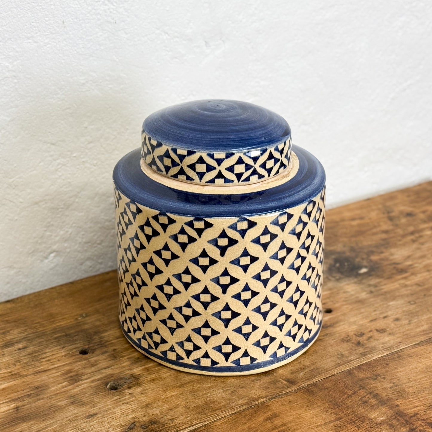 Ceramic jar with blue and beige geometric pattern on a wooden surface