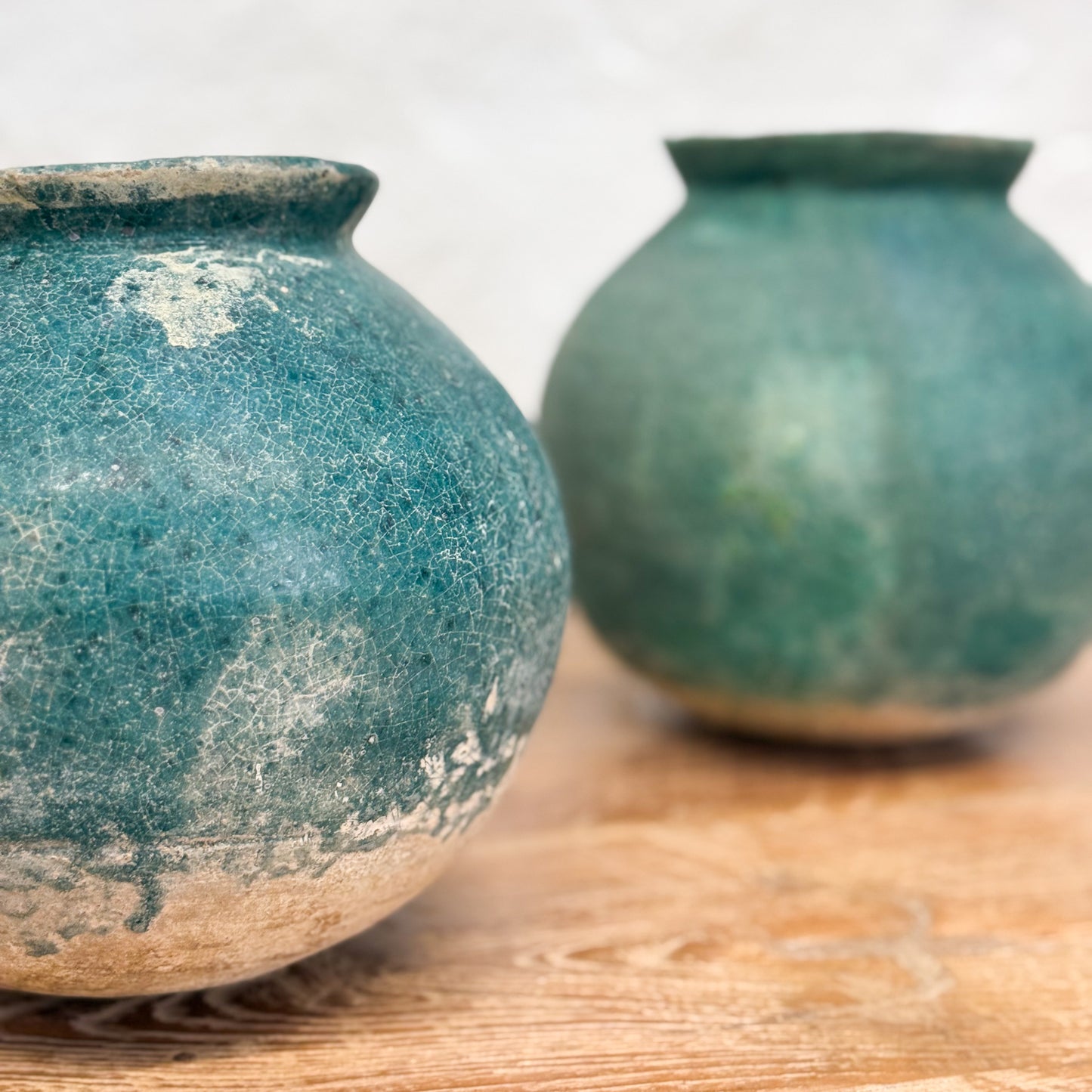 Two blue ceramic pots on a wooden surface with a white background
