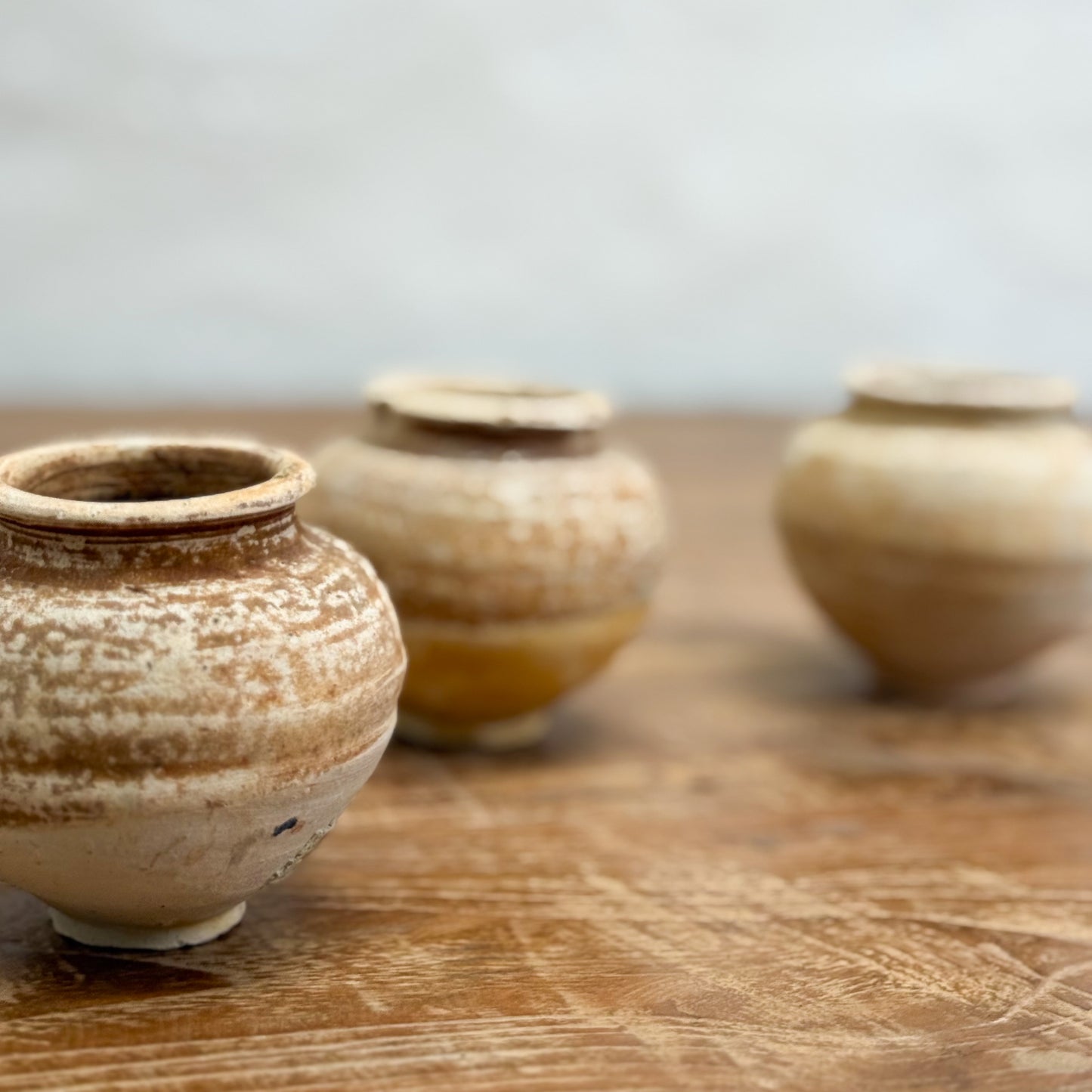 Three ceramic pots on a wooden surface with a blurred background