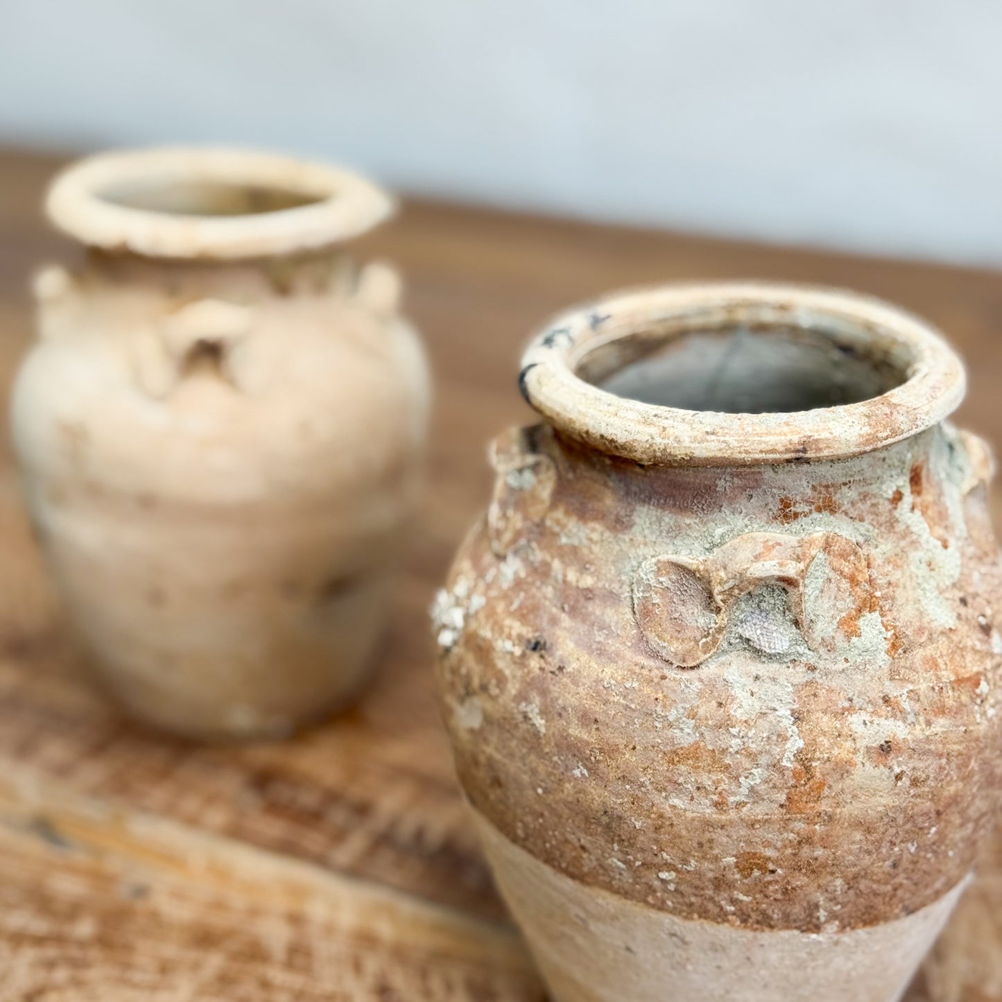Two rustic clay pots on a wooden surface with a blurred background