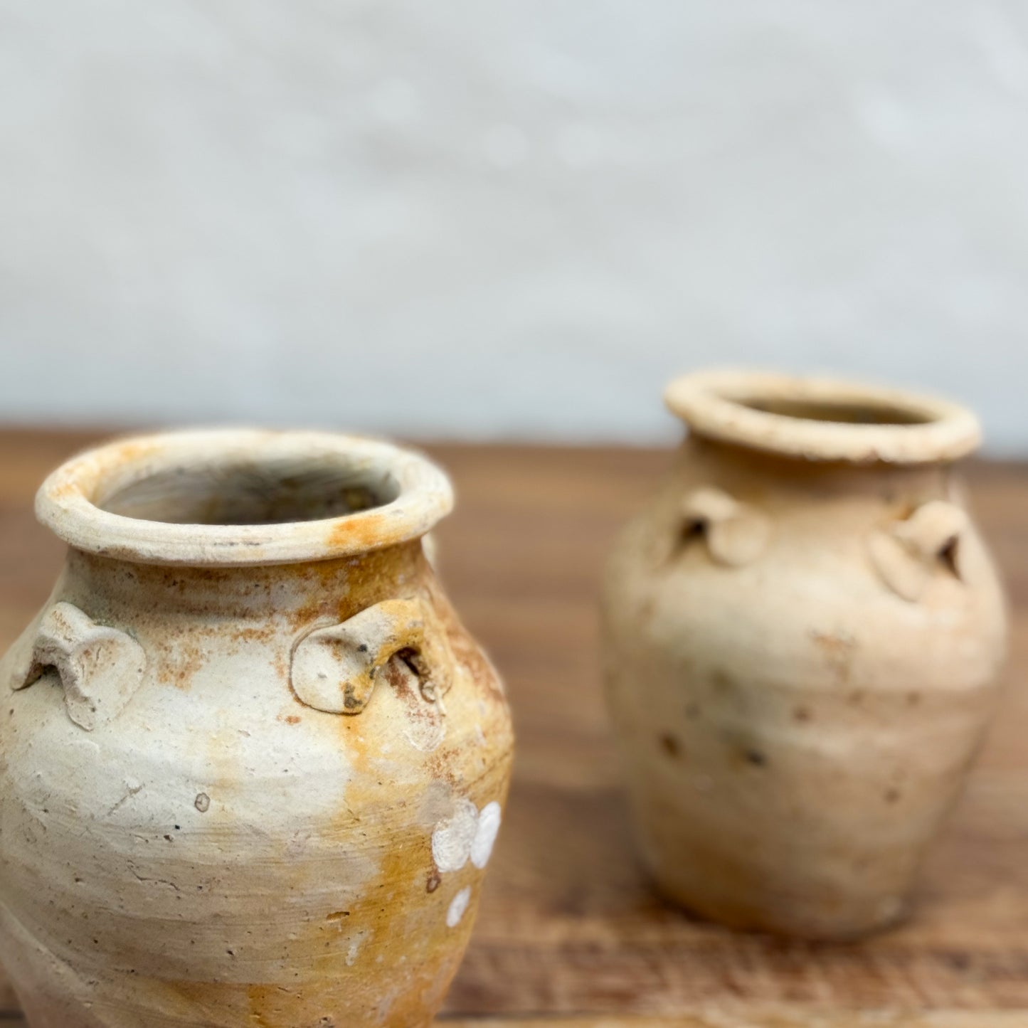 Two ceramic jars with handles on a wooden surface