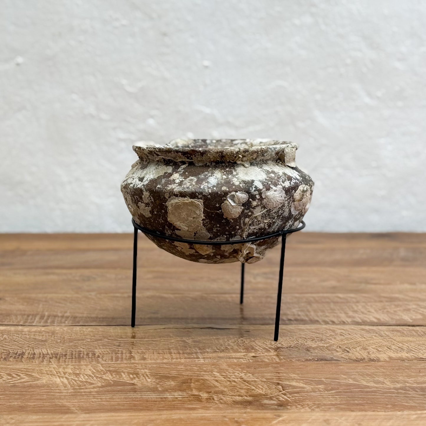 Decorative stone pot on a stand against a neutral background