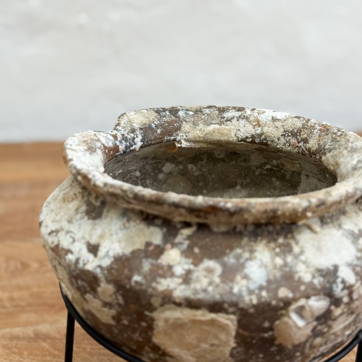 Vintage-style terracotta pot on a stand with a neutral background