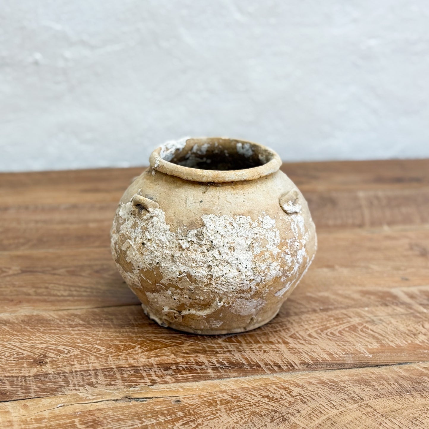 Vintage ceramic pot on a wooden surface with a neutral background