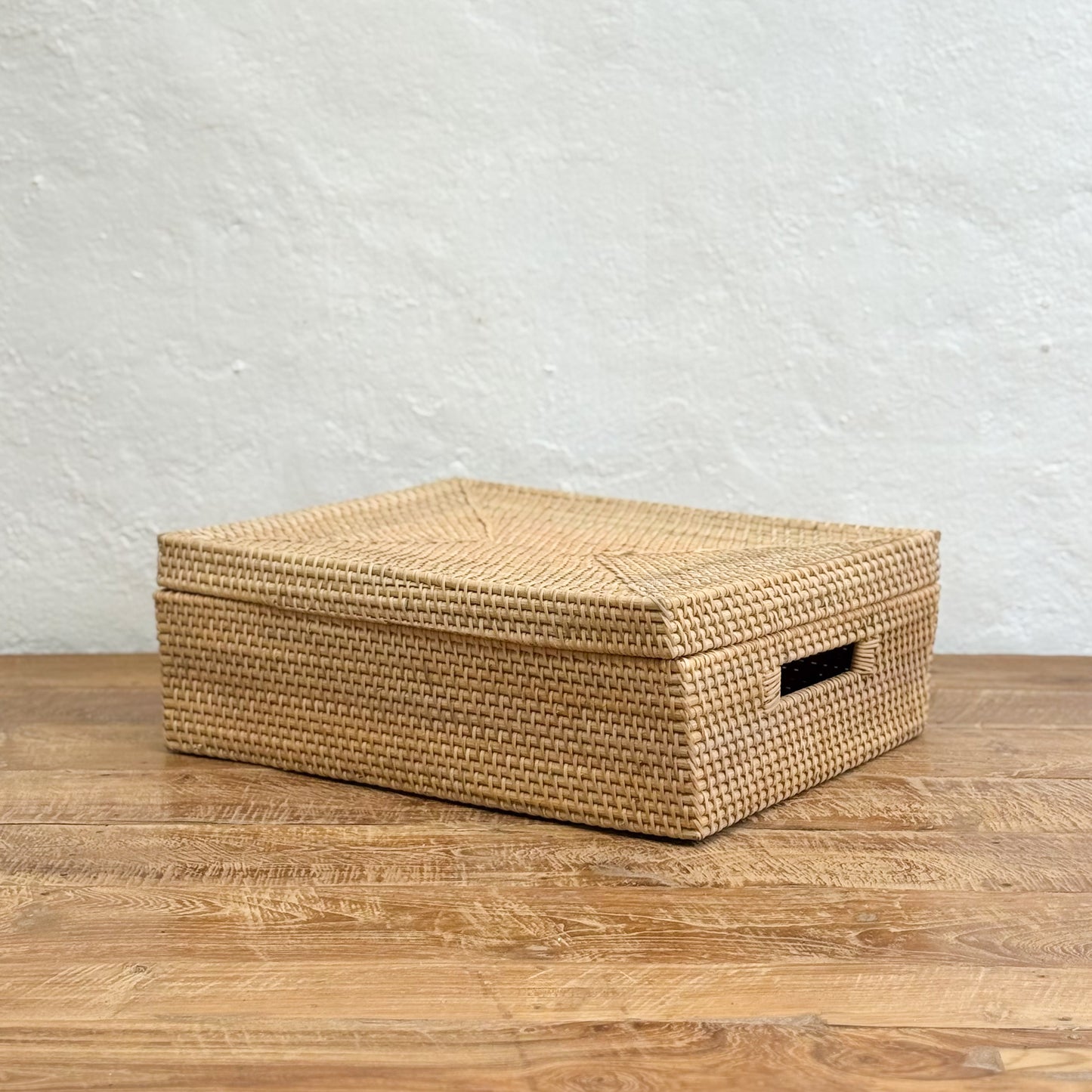 Woven storage box on a wooden surface with a light gray textured wall background