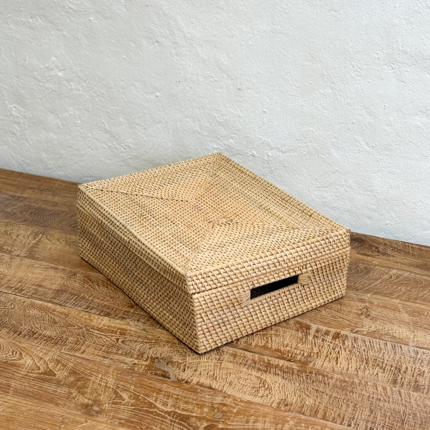 Woven storage box on a wooden surface with a light gray wall background