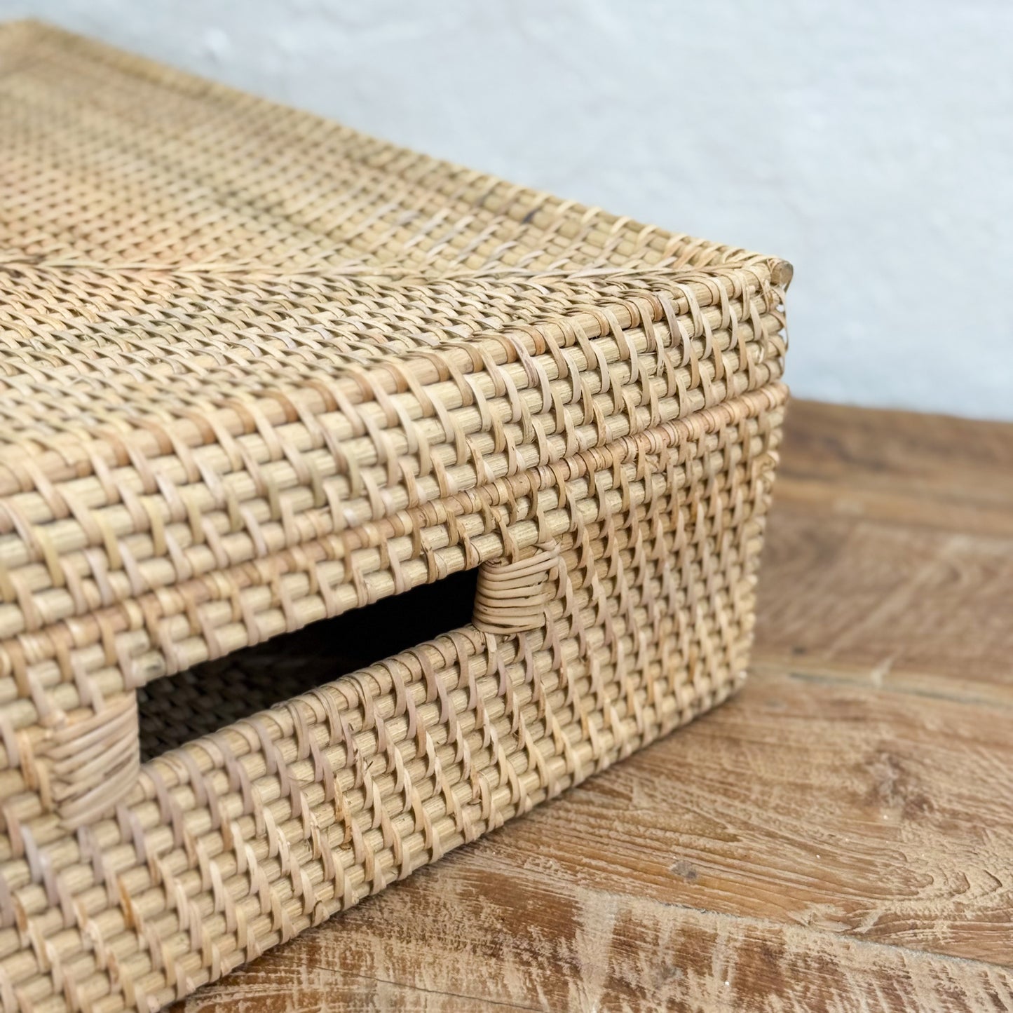 Woven rattan box on a wooden surface with a light blue background
