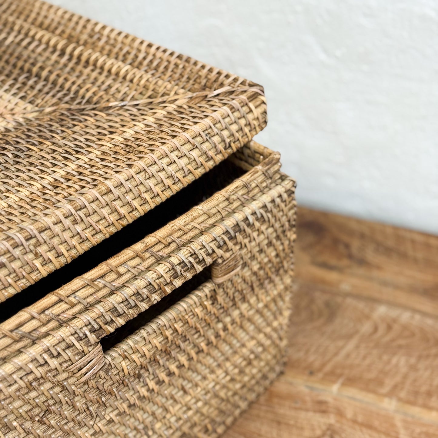Stack of woven baskets on a wooden floor with a white wall background