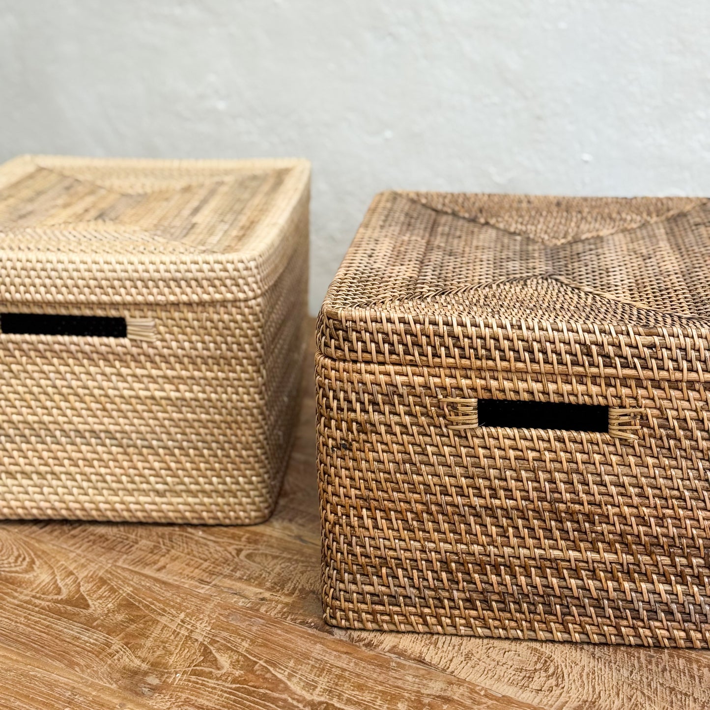 Two woven storage boxes on a wooden surface with a light gray background