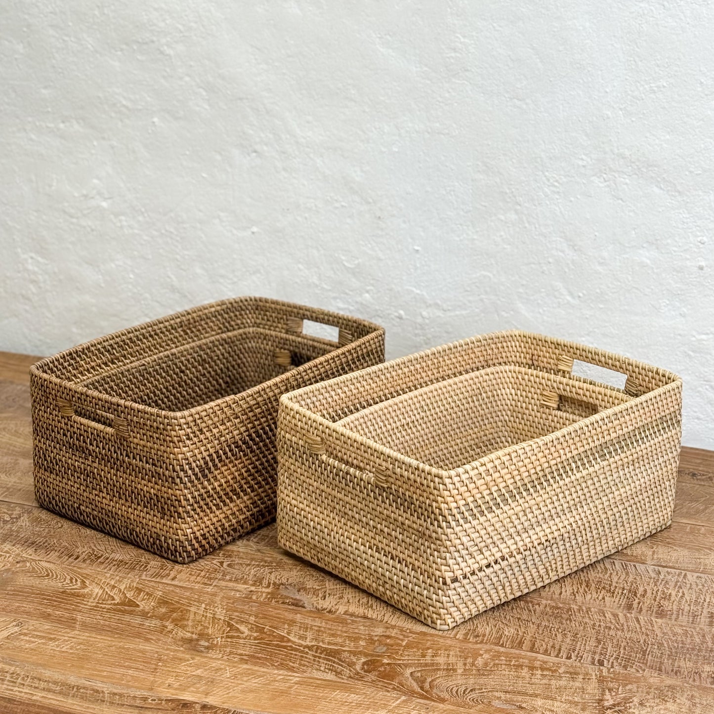 Two woven baskets on a wooden surface with a light gray textured wall background
