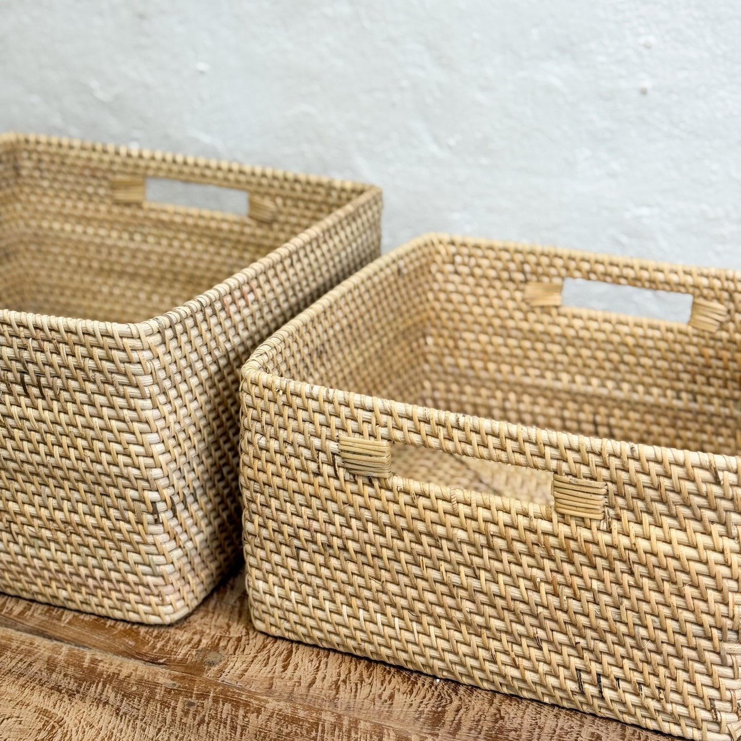 Two woven baskets on a wooden surface with a neutral background