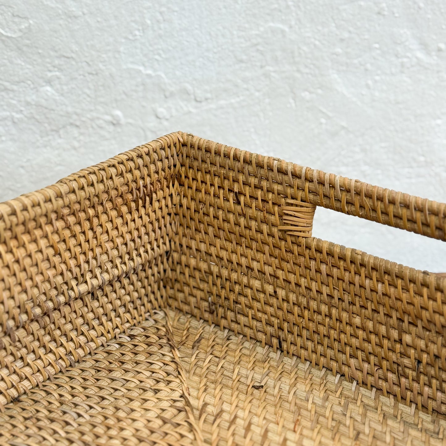 Woven rattan basket with a handle on a light gray background
