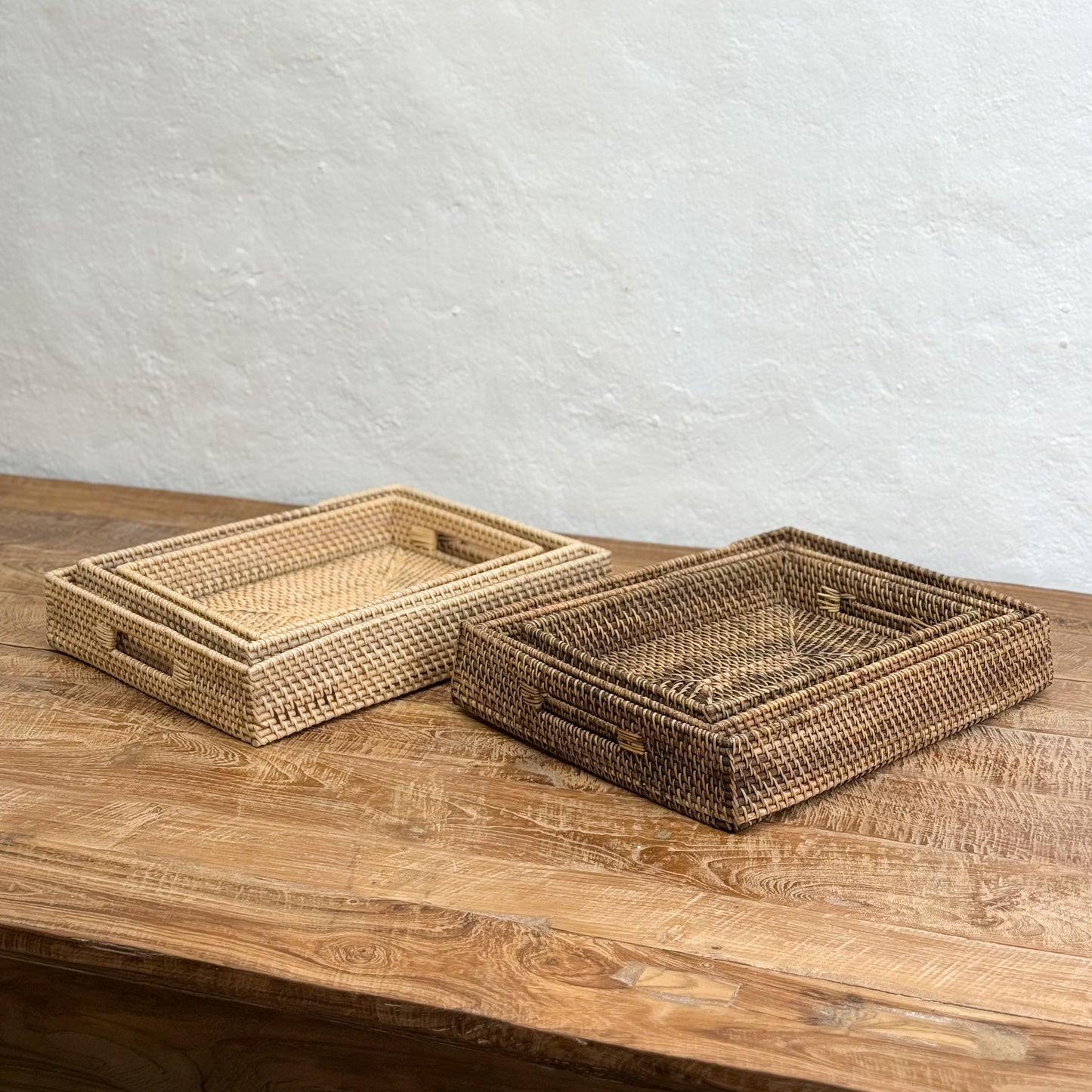 Two woven baskets on a wooden surface with a light gray background