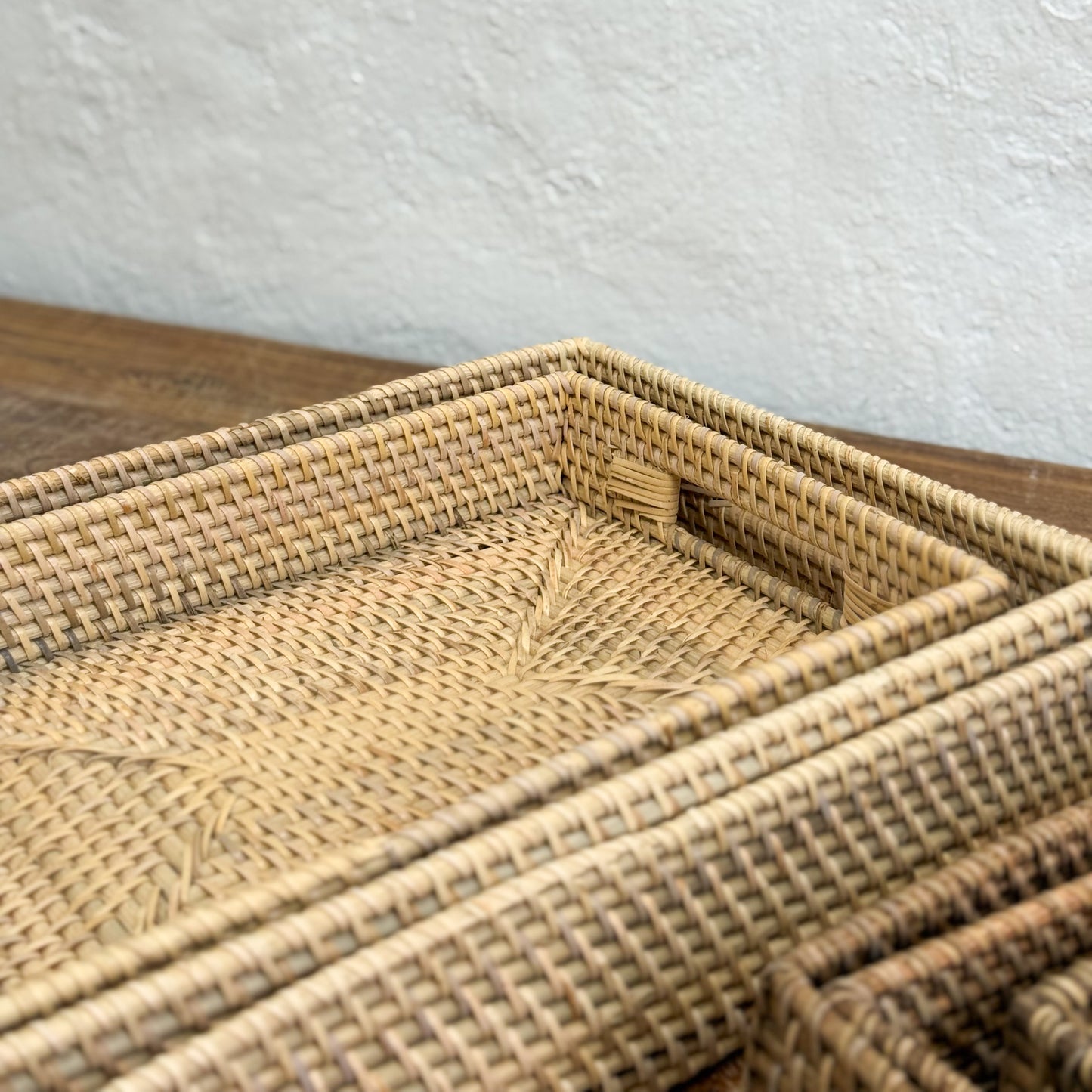 Woven rattan tray on a wooden surface with a light gray background