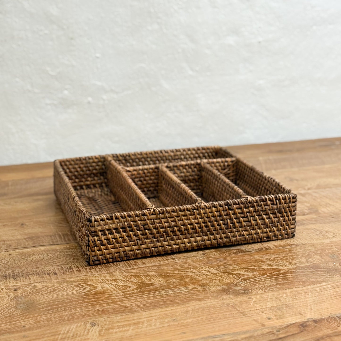 Woven rattan tray on a wooden surface with a light gray background