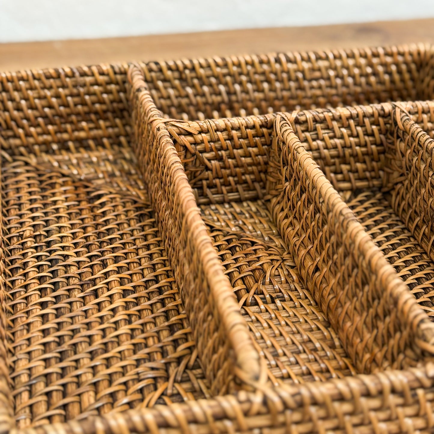 Woven rattan tray with compartments on a wooden surface
