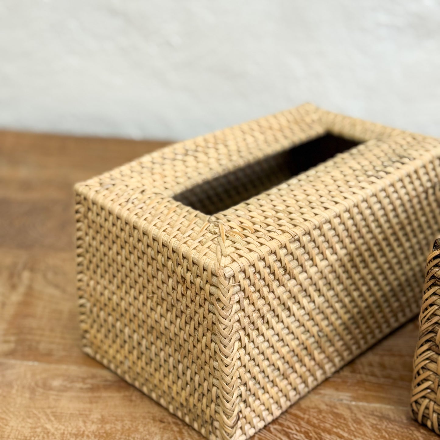 Woven tissue box on a wooden surface with a neutral background