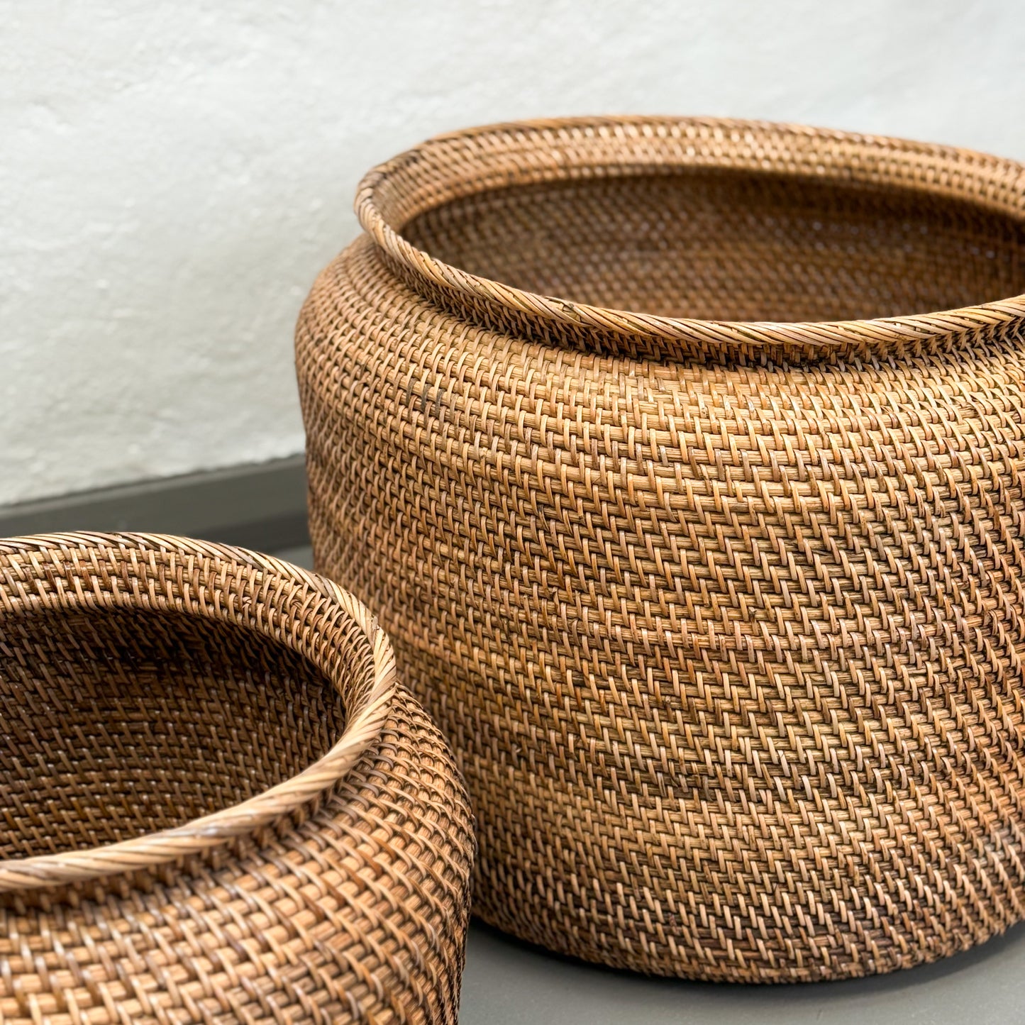 Two woven baskets on a light gray surface with a neutral background