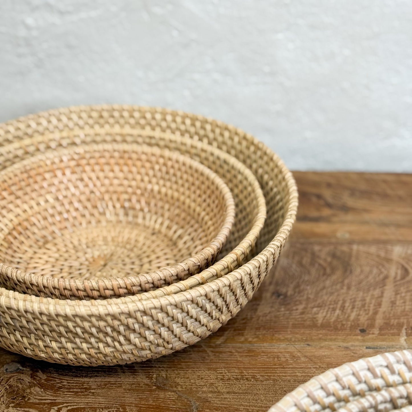 Stack of woven baskets on a wooden surface with a neutral background