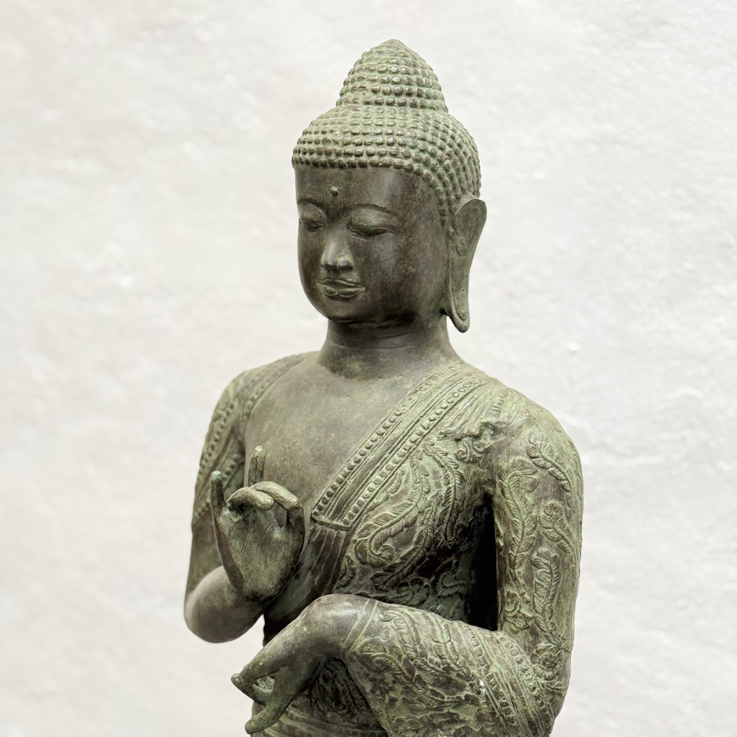 Bronze statue of a seated Buddha on a white background