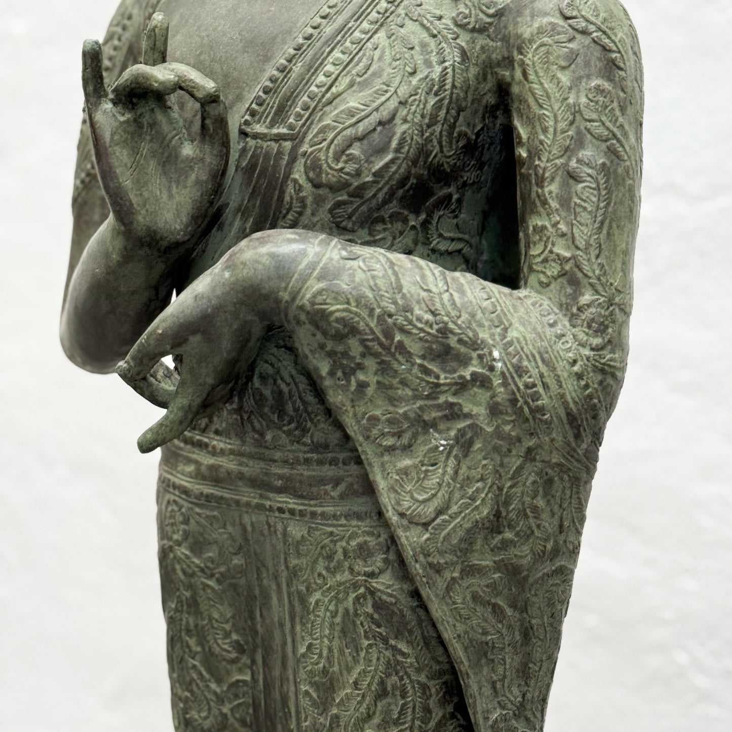 Bronze statue of a figure with intricate patterns on a white background