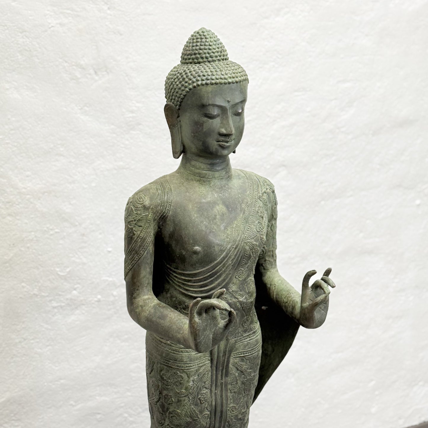 Statue of a Buddha figure on a textured white background