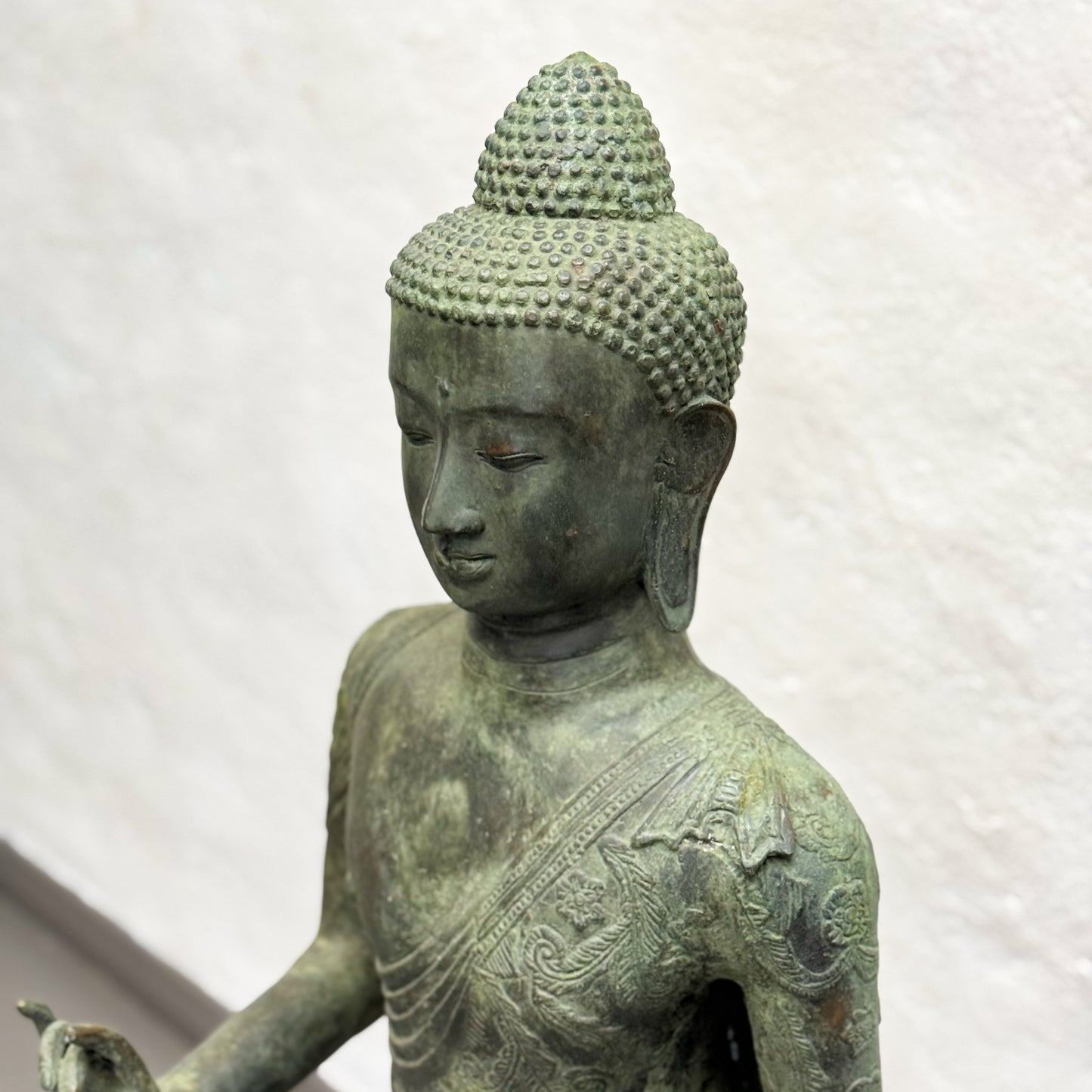 Bronze statue of a seated Buddha on a white background