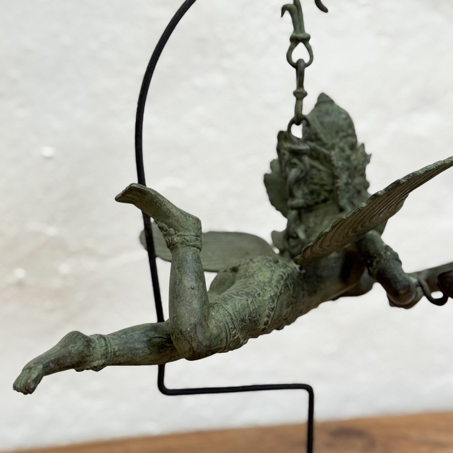 Bronze sculpture of a winged figure on a stand with a neutral background