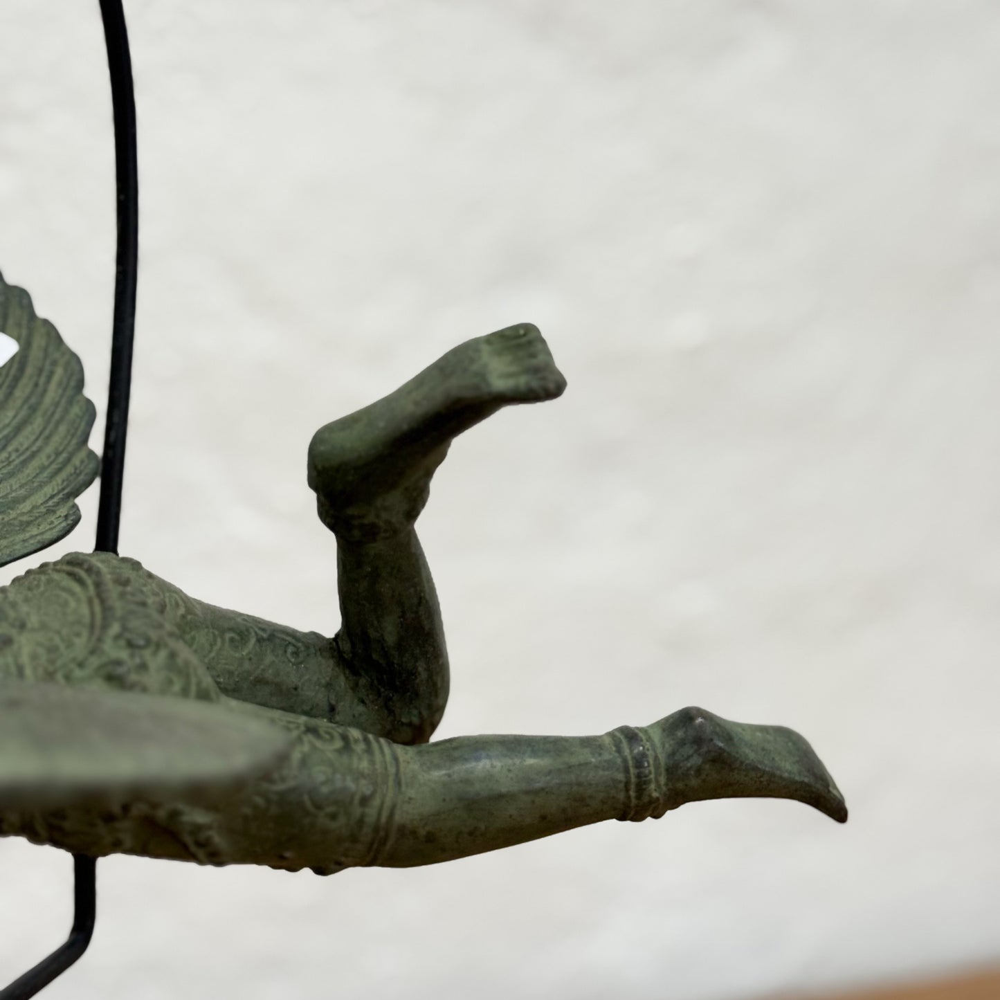 Bronze sculpture of a figure with outstretched arms and legs on a plain background