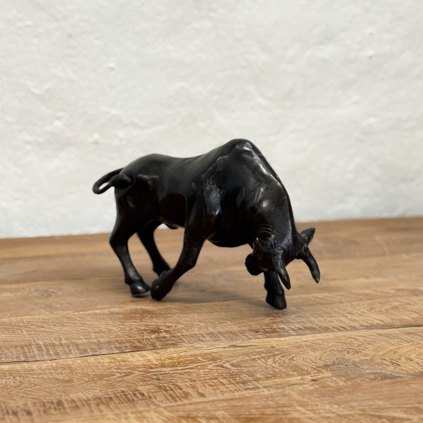 Black bull figurine on a wooden surface with a light gray textured background