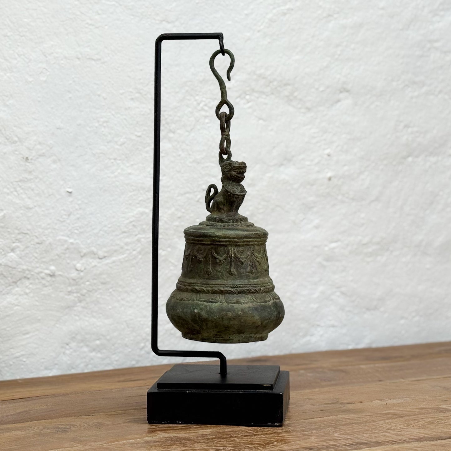 Bronze bell on a stand against a textured white wall