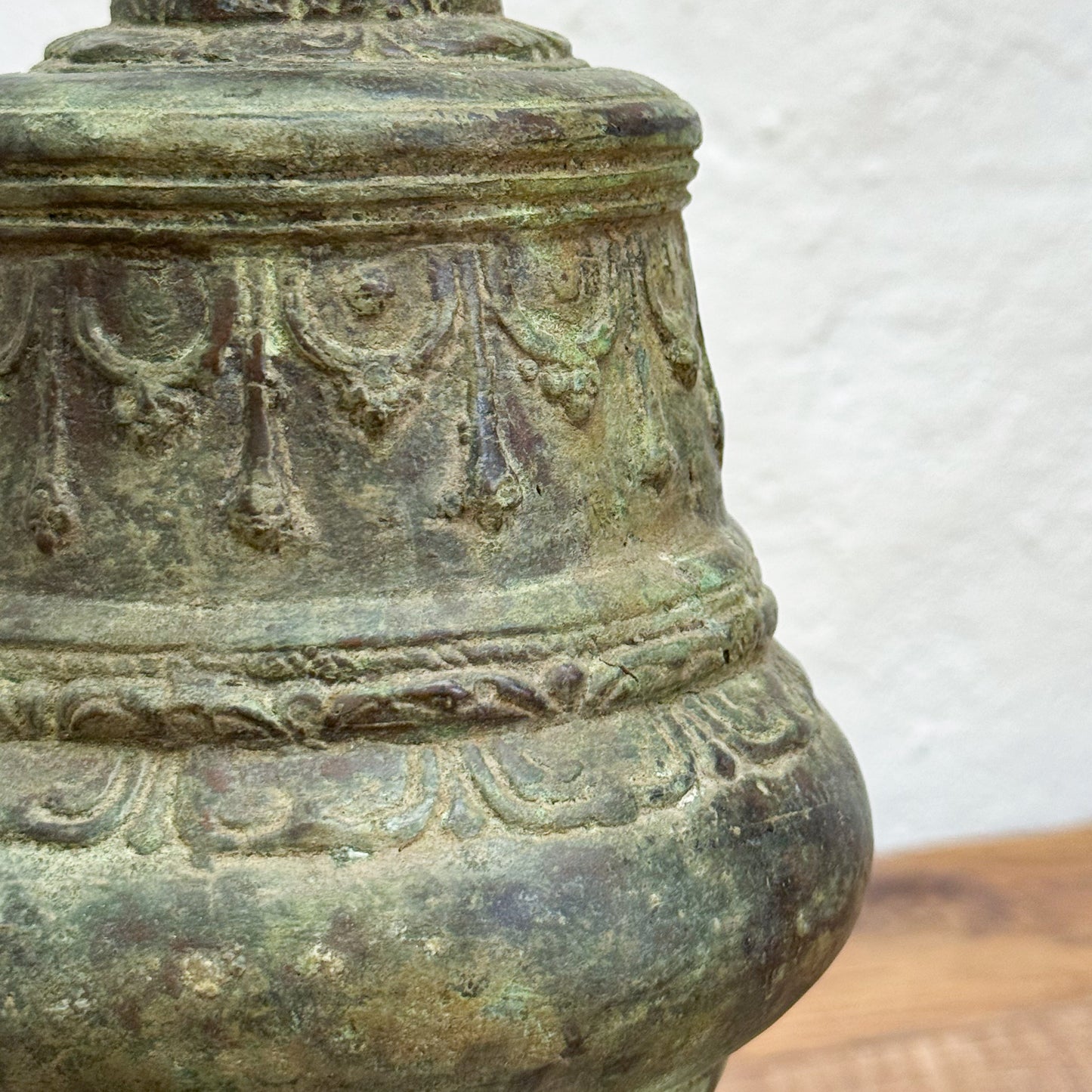Close-up of an ancient bronze bell with intricate designs on a white background