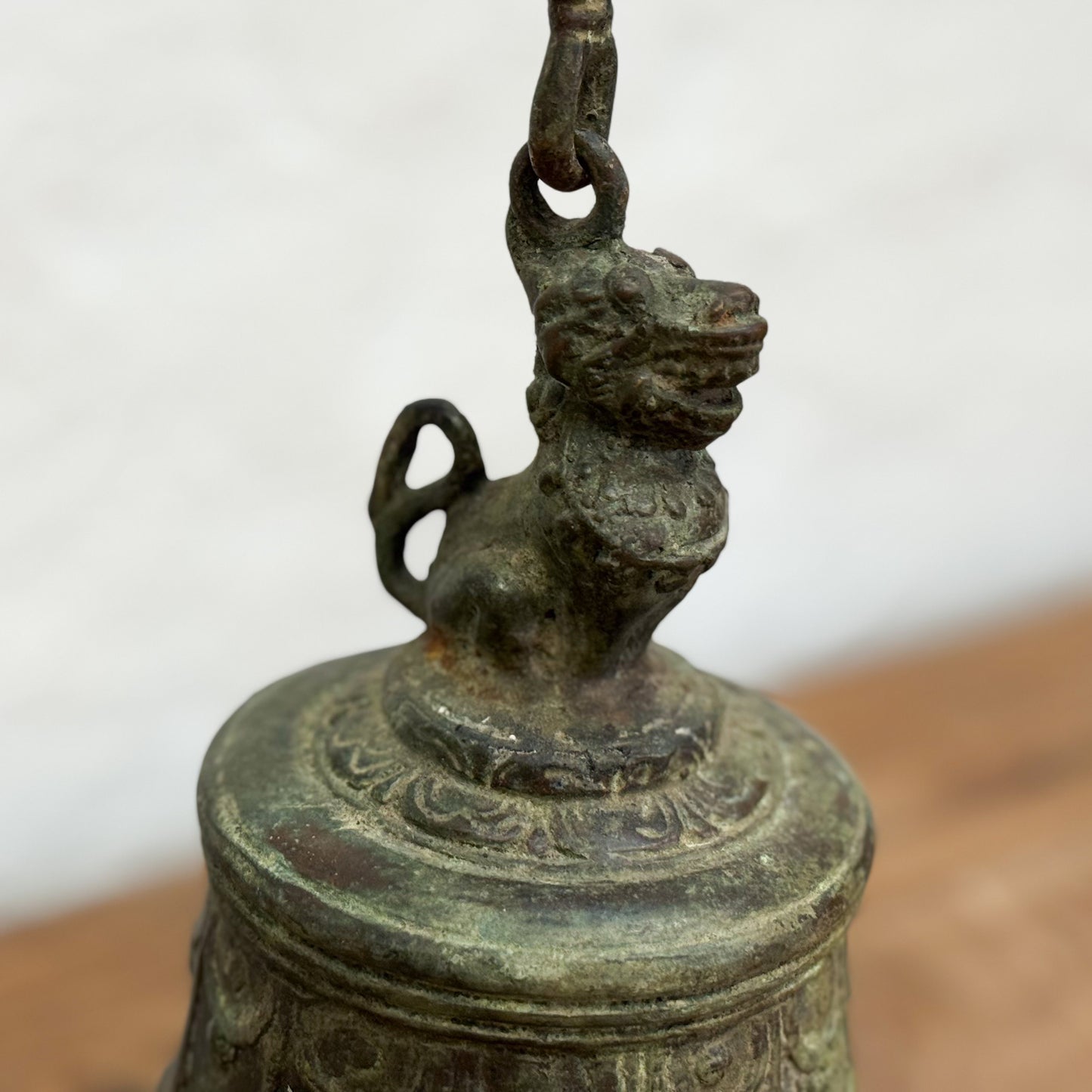Bronze bell with lion-shaped finial on a plain background