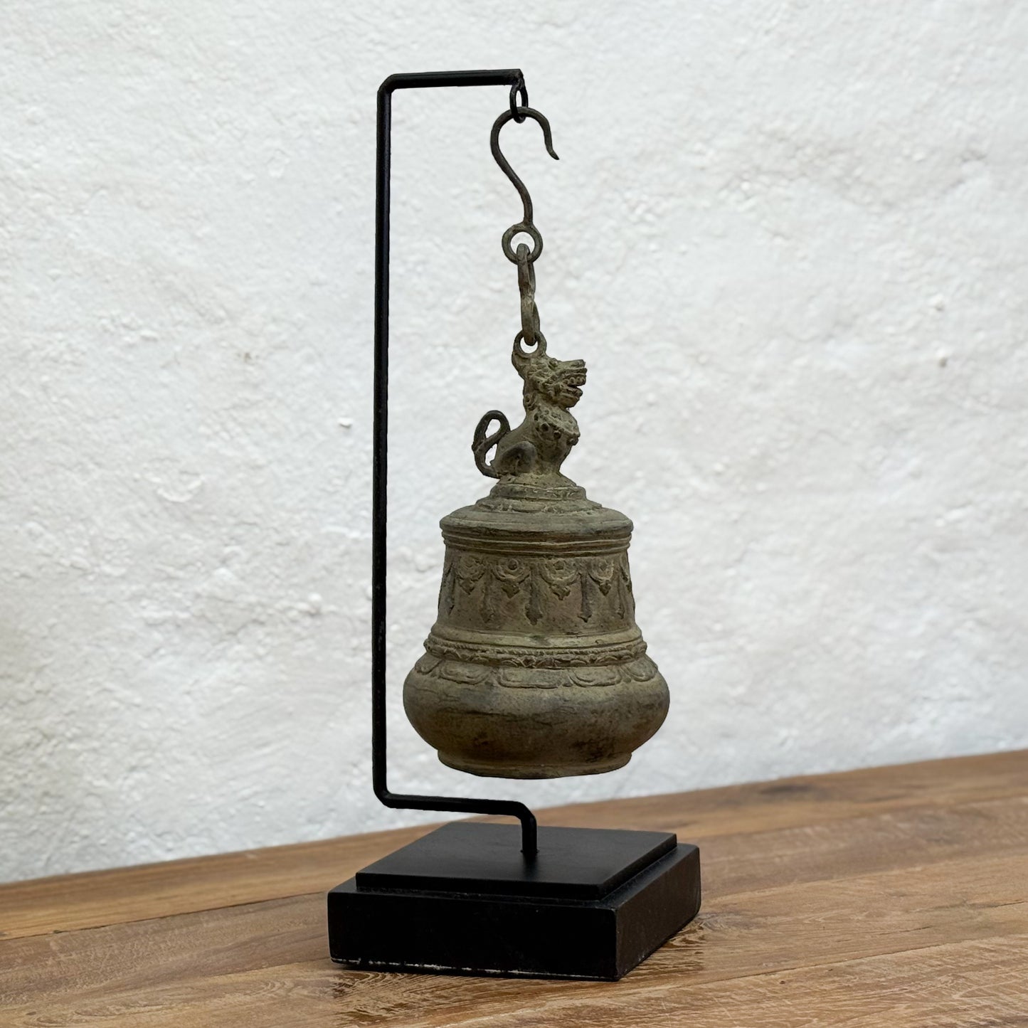 Bronze bell on a stand against a textured white wall