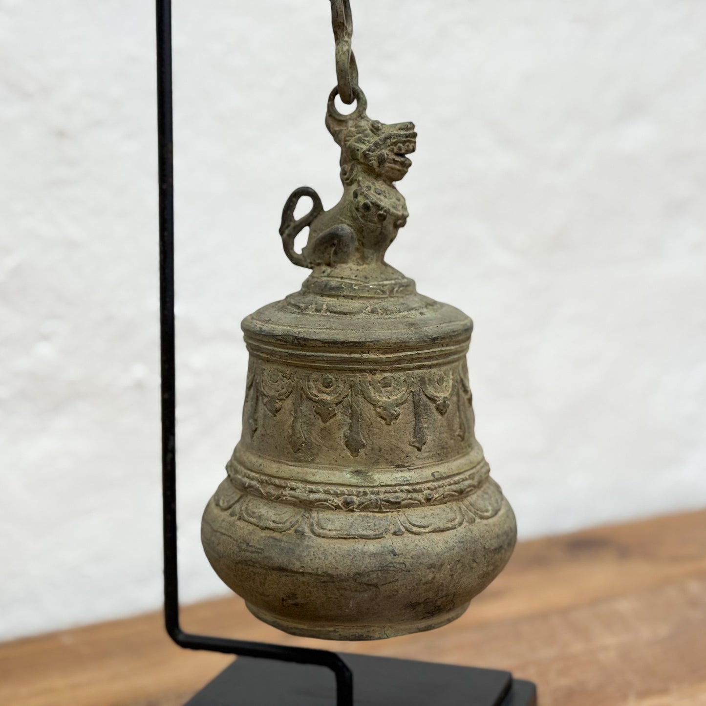 Bronze bell with decorative elements on a stand against a white background