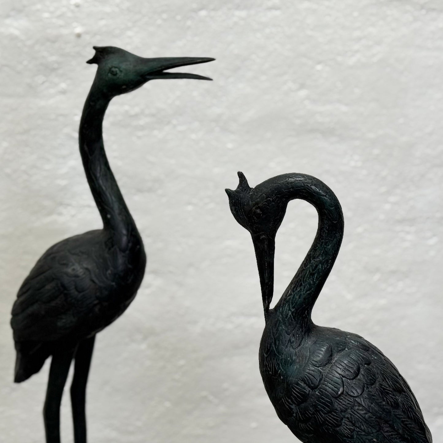 Two black bird figurines on a textured white background
