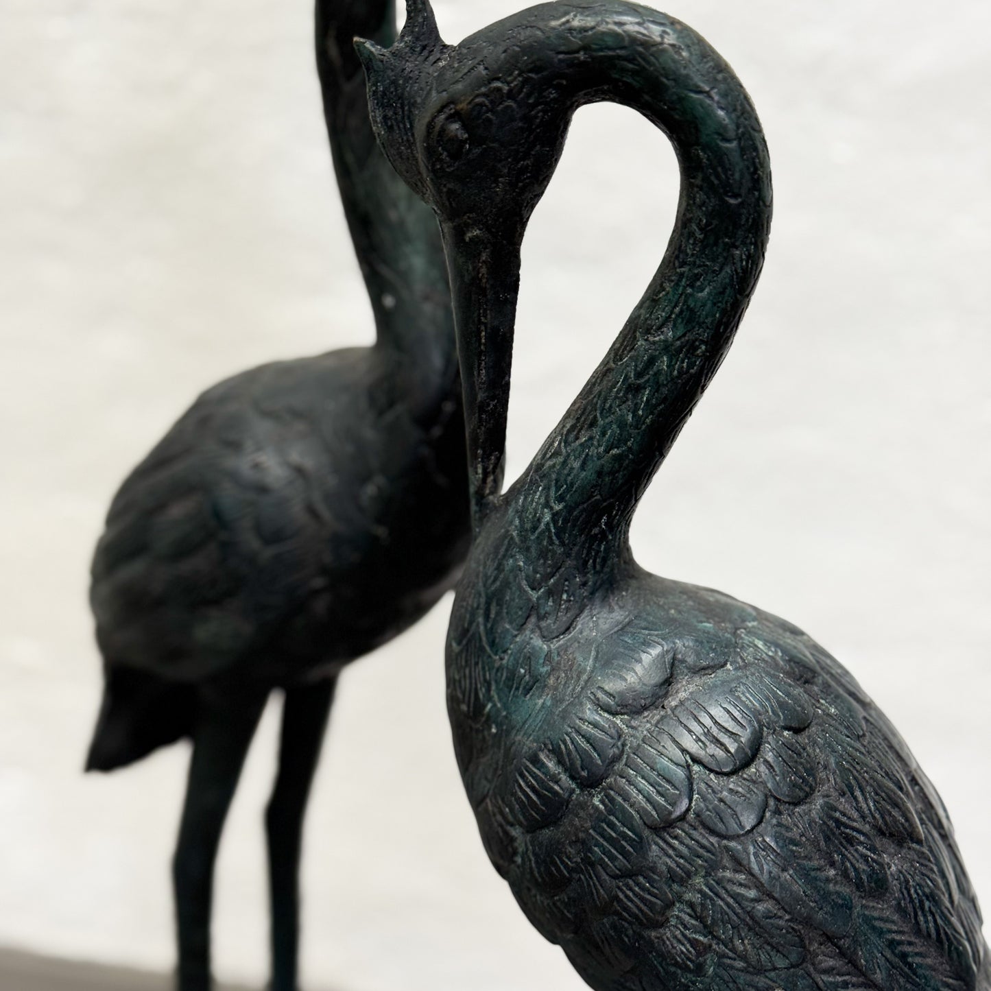Bronze sculpture of two cranes intertwined on a light background