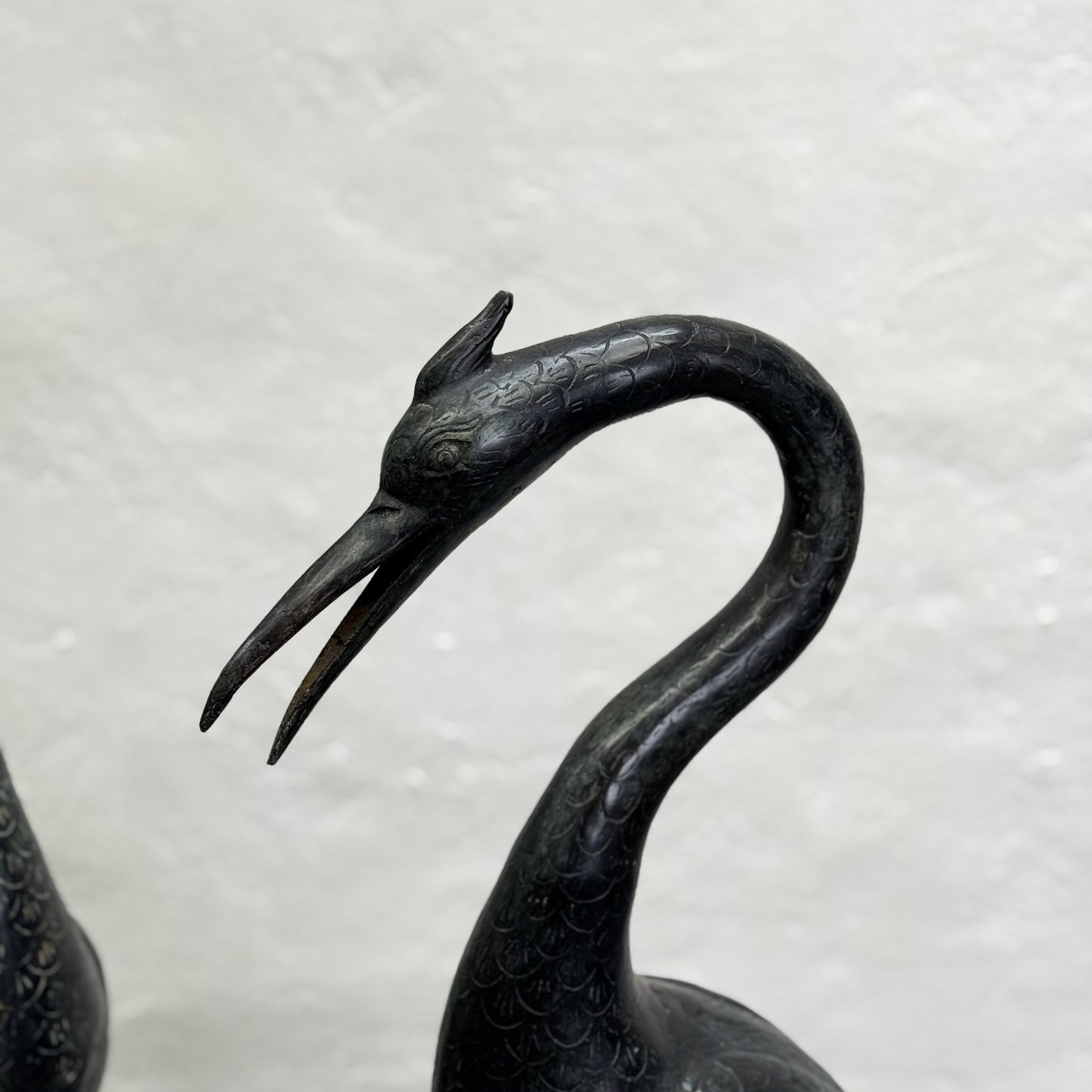 Bronze crane sculpture on a light gray background