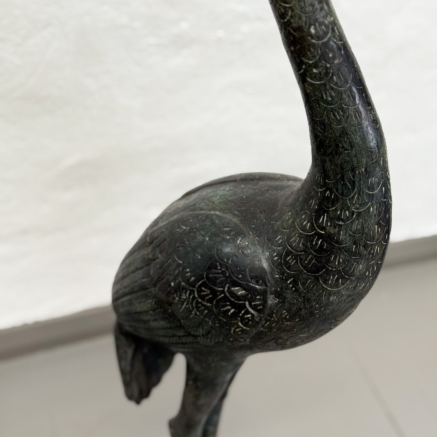 Bronze sculpture of a bird with detailed patterns on a white background