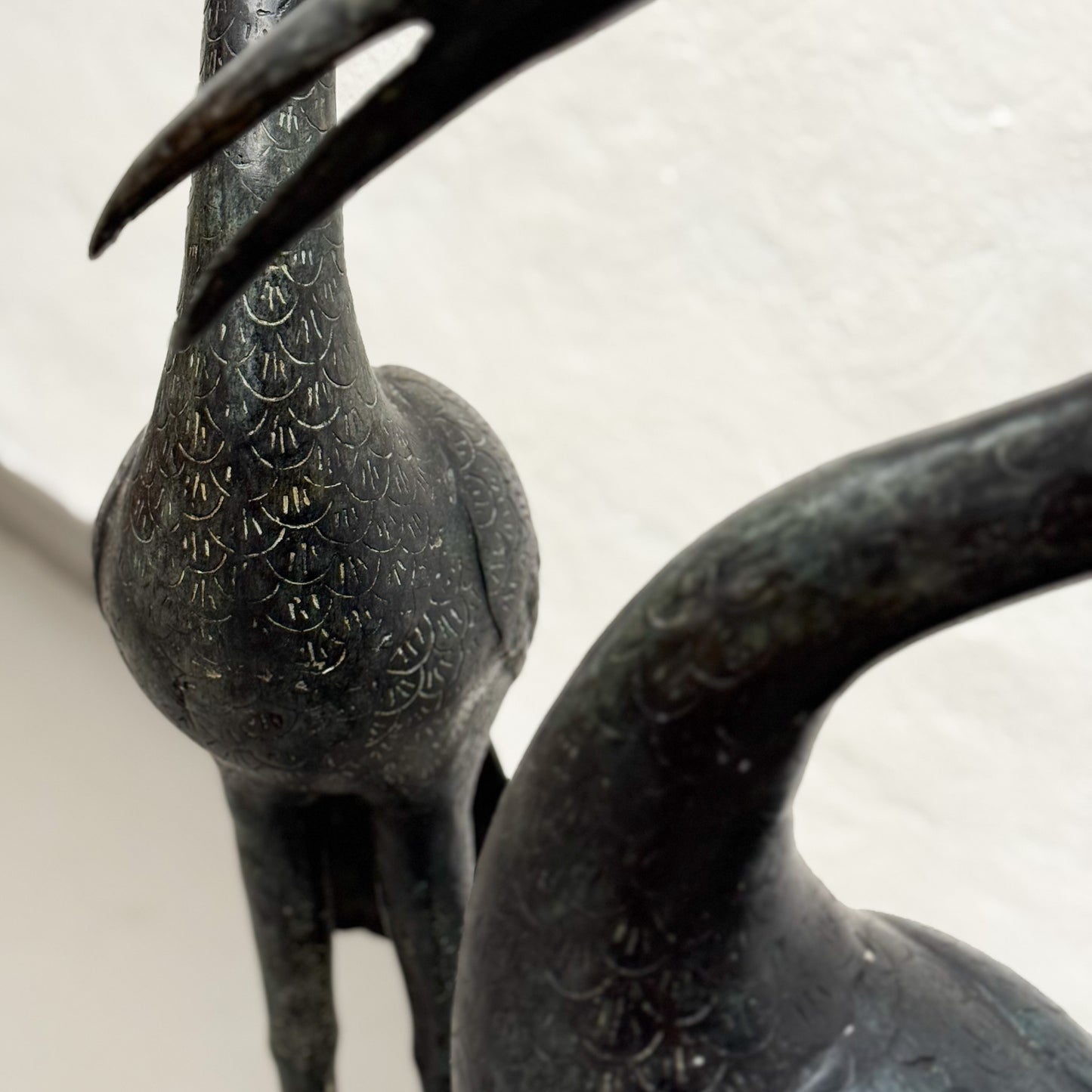 Bronze sculpture of two cranes on a light background