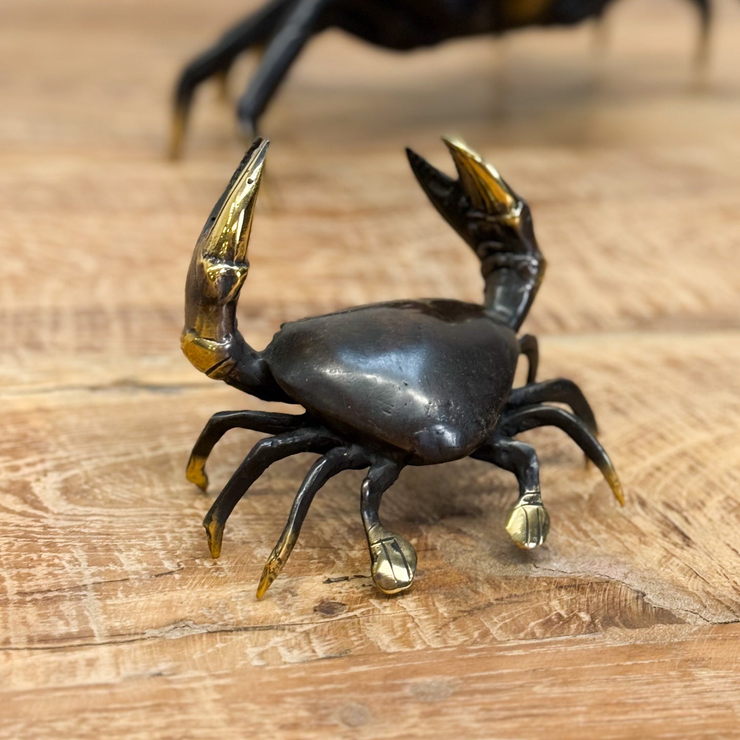 Black crab figurine with gold accents on a wooden surface