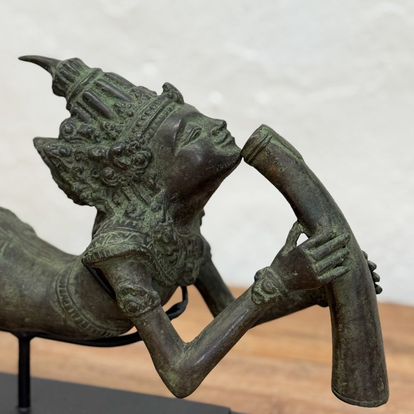 Bronze statue of a figure holding a weapon against a neutral background