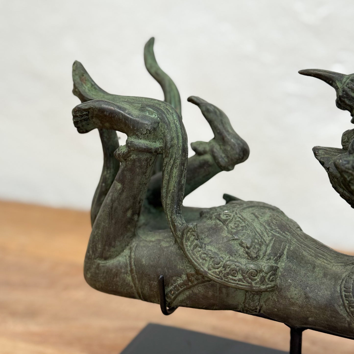 Bronze sculpture of a creature with large horns on a wooden surface.