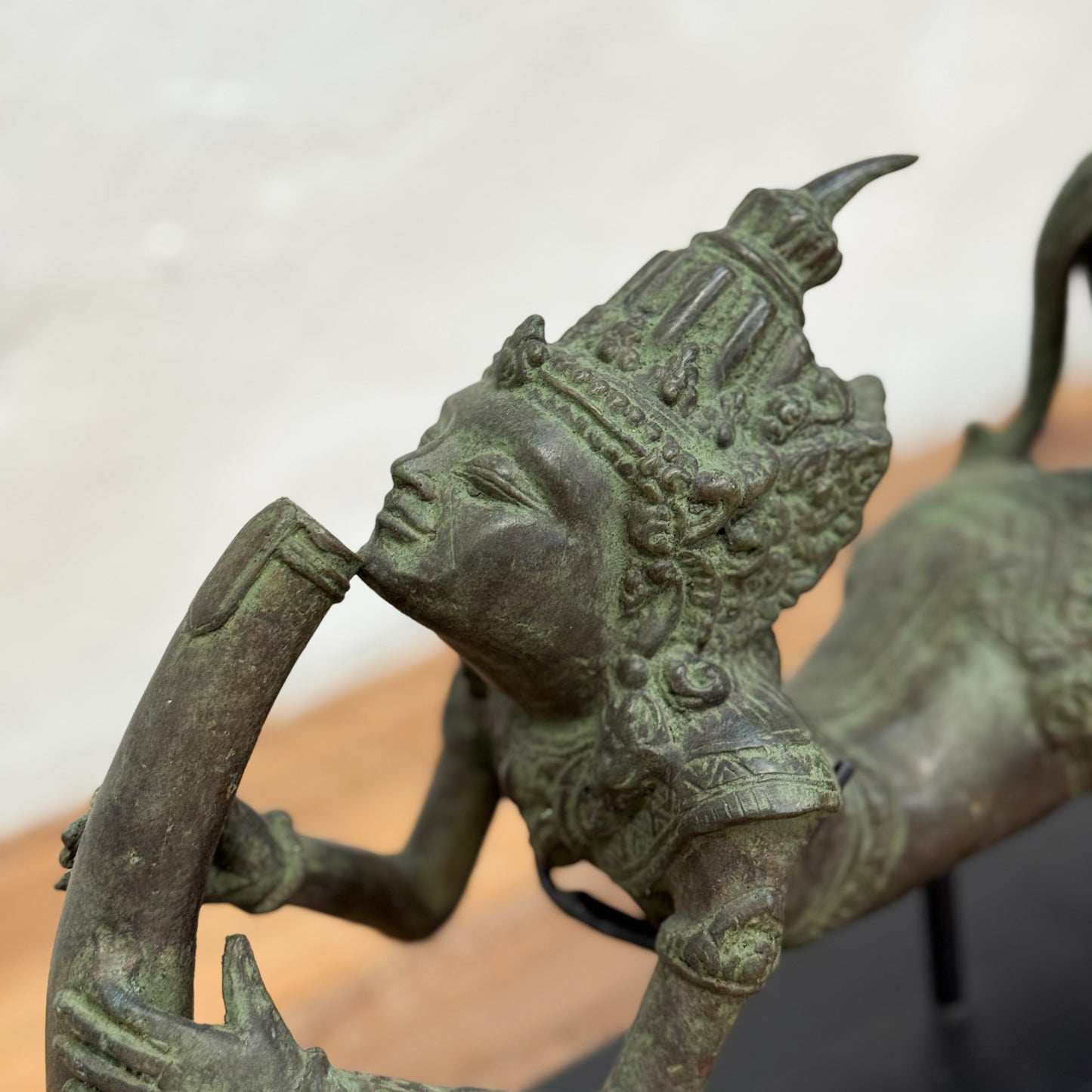 Bronze statue of a figure with intricate detailing on a plain background