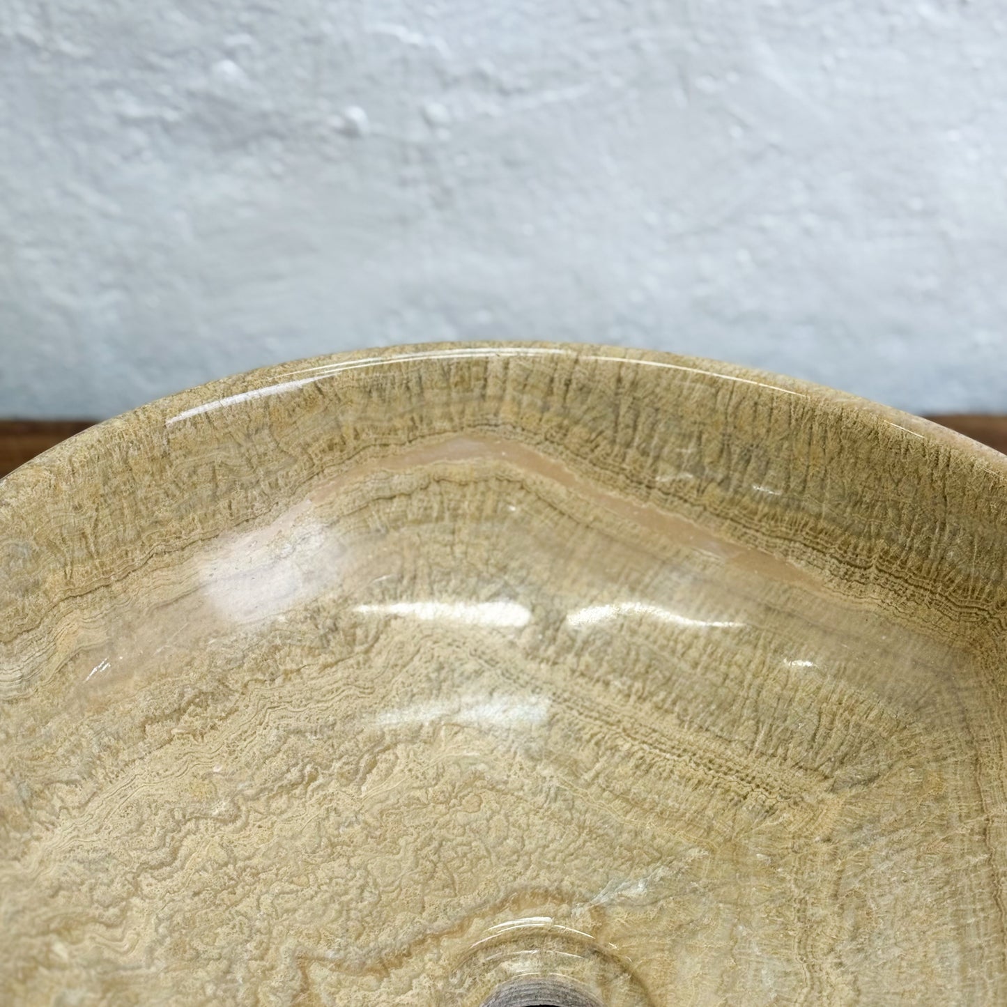 Beige ceramic sink with textured surface on a light gray background