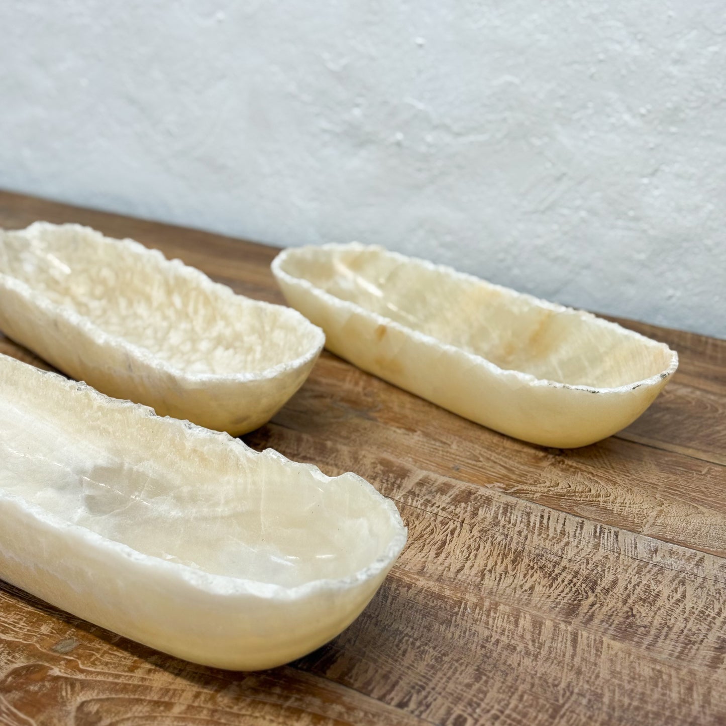 Three raw bread loaves on a wooden surface with a white background