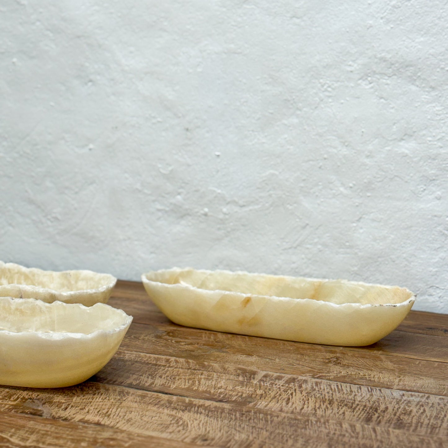 Three raw pie crusts on a wooden surface with a light gray textured background