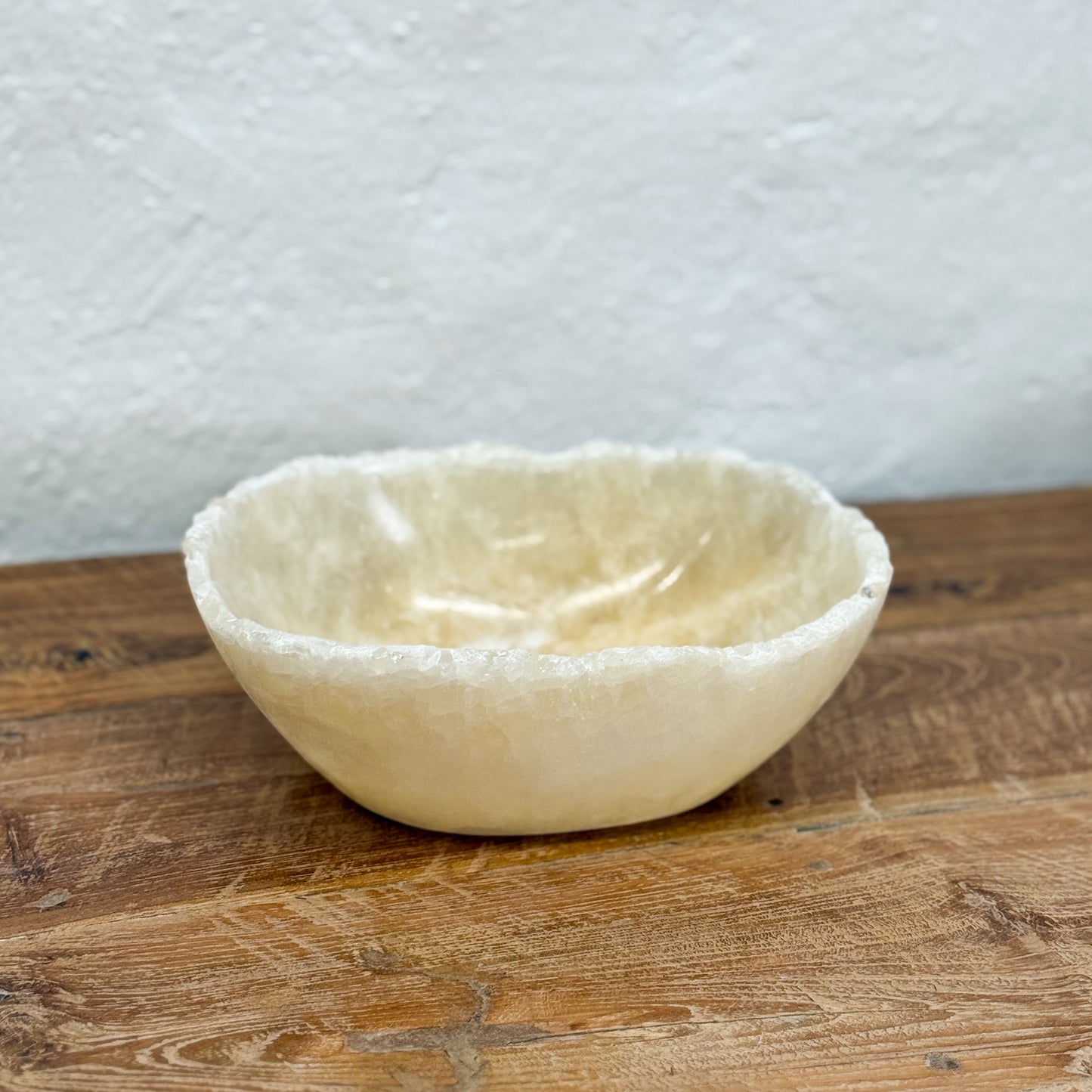 White stone bowl on a wooden surface with a white wall background