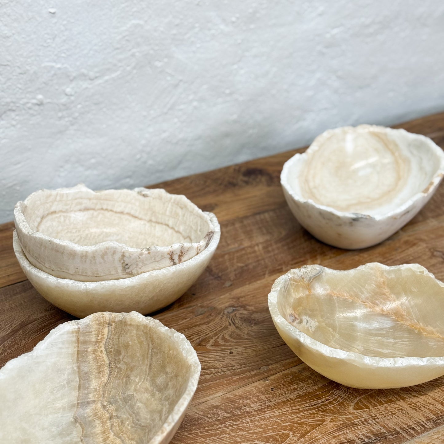Four natural stone bowls on a wooden surface with a white background